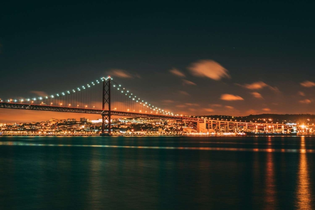 lisbon’s 25 de abril bridge at night, showing the benefits of buying property in portugal.