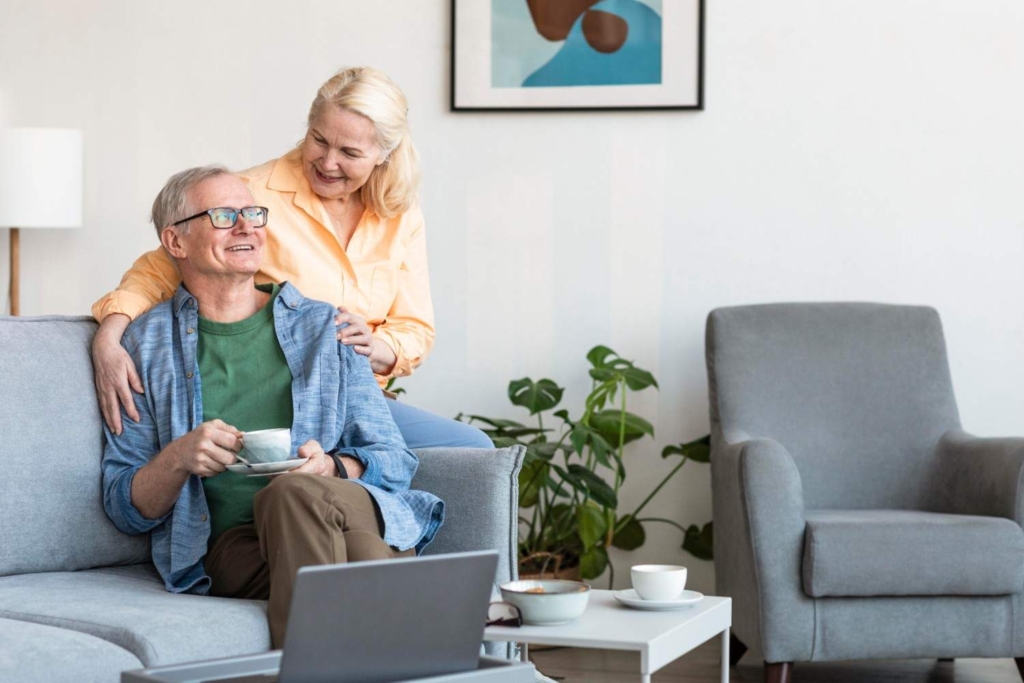 senior couple planning retiring to italy at home with laptop and coffee