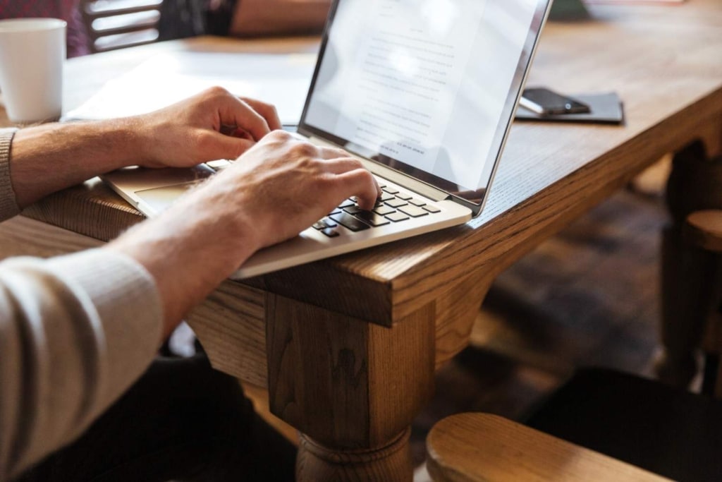 property marketing copywriting on a laptop at a wooden desk in a workspace setting.