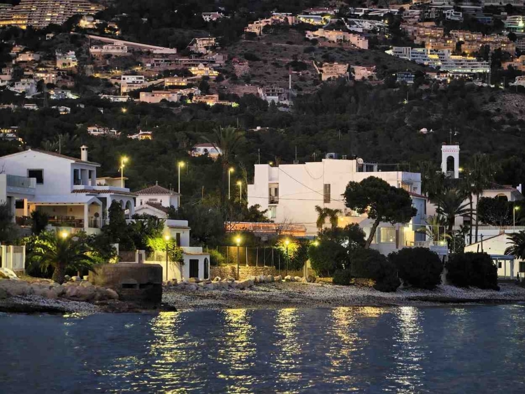 houses for sale by the sea in spain with coastal villas and waterfront homes at sunset.